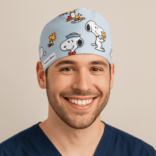 Smiling male doctor wearing a light blue cartoon scrub cap featuring Snoopy and Woodstock print. Adjustable and comfortable men’s surgical hat perfect for surgeons, doctors, or pediatric staff. A fun, professional, and thoughtful custom gift for doctors in the OR or clinic.