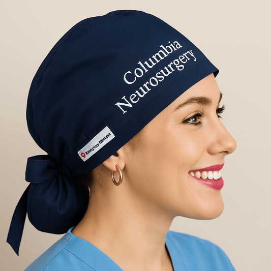 Smiling woman wearing a solid navy blue ponytail scrub cap embroidered with “Columbia Neurosurgery.” Custom name surgical hat with ribbon ties, designed for women nurses and doctors. Comfortable, professional, and ideal for hospital or OR use.
