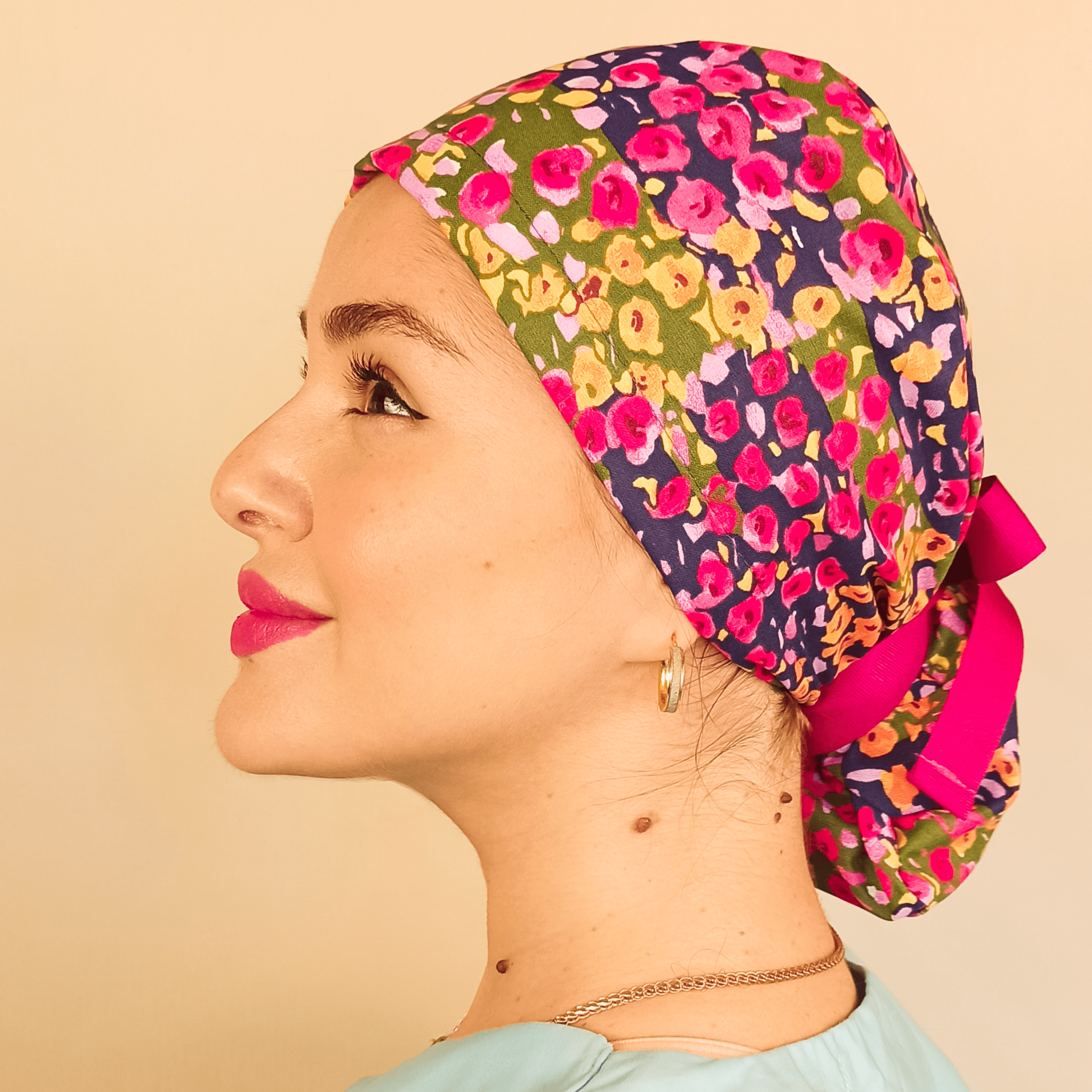 Floral custom satin lined scub cap for women pink ribbon for your ponytail at back, a nurse wearing and smilling this floral scrub cap