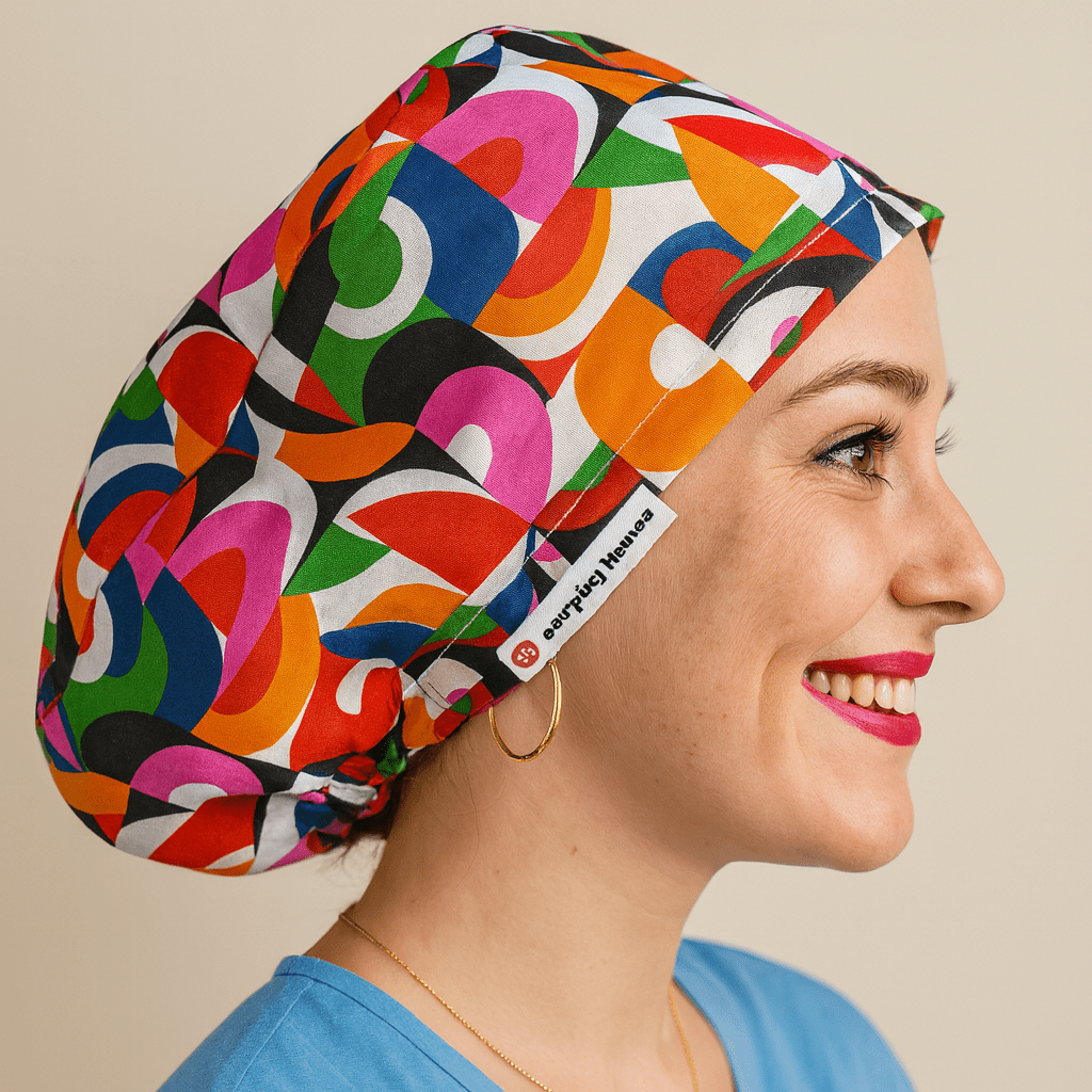 Smiling woman wearing a retro-inspired euro scrub cap with bold geometric shapes in pink, orange, green, and blue. Colorful satin-lined surgical hat for nurses and medical professionals. Comfortable and stylish, ideal for long hospital shifts or clinical settings.