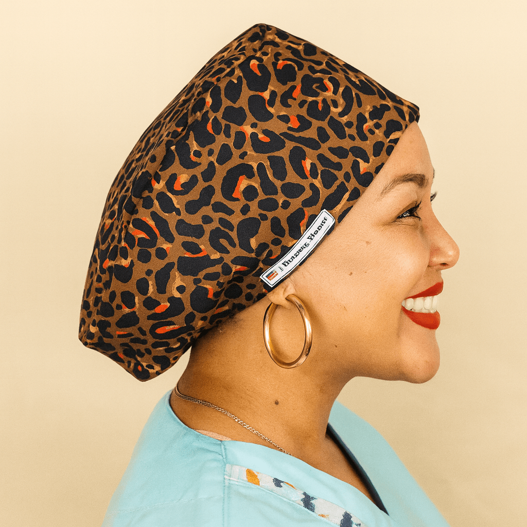 leopard scrub cap for women , the women on the photo is black and she is smiling as she wearing the cheetah cotton print scrub hat euro style on her head ,