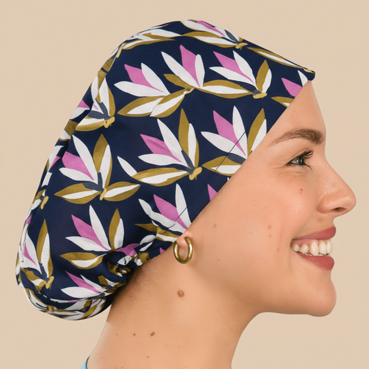 Smiling woman wearing a navy floral euro scrub cap with pink and olive leaf print. Custom satin-lined surgical hat for nurses, surgeons, and estheticians. Lightweight, stylish, and professional scrub cap providing comfort and hair protection during long shifts.