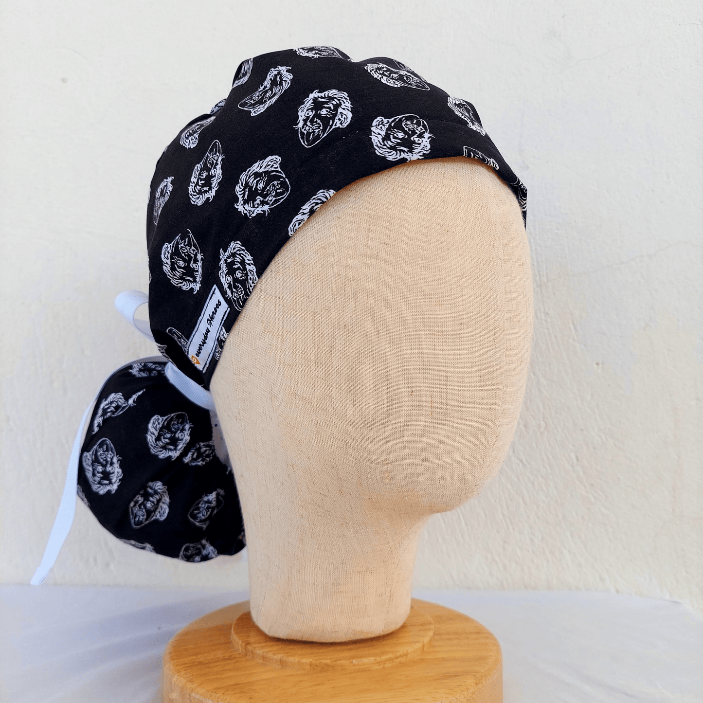 Ponytail scrub cap featuring a playful Einstein face print, designed with adjustable ribbon ties and an absorbent sweatband. Perfect for nurses, surgeons, and doctors who want comfort and personality in the operating room.