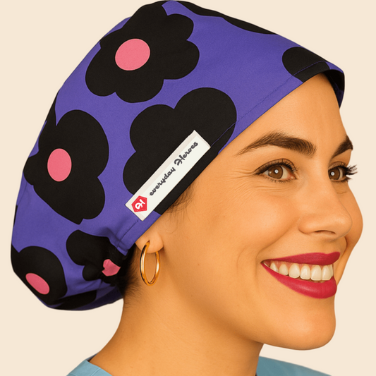 A woman wearing a purple cap with a black flower pattern and a red heart logo, smiling at the camera.
