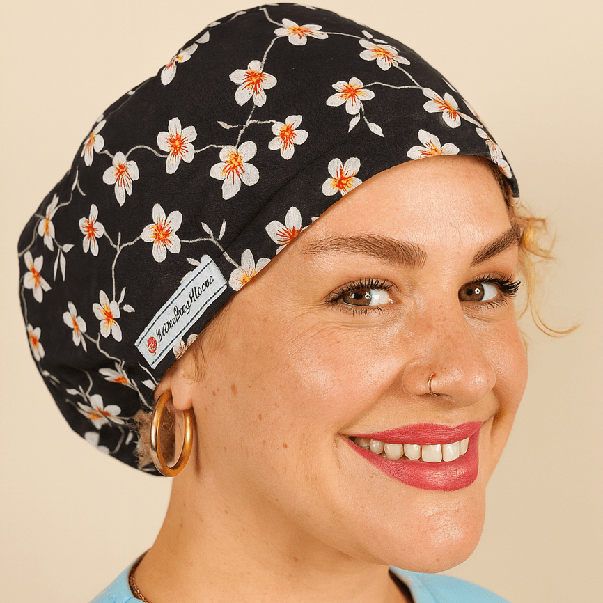 A woman wearing a black and white floral patterned cap and a light blue shirt is smiling at the camera.