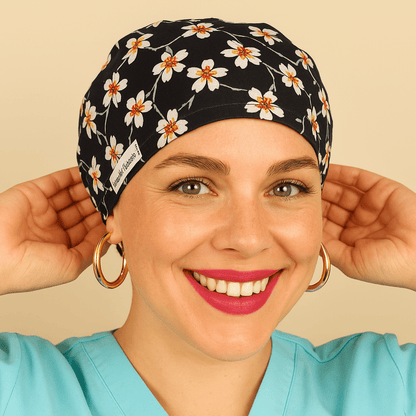 A woman wearing a black and white floral patterned headband and a turquoise shirt is smiling and adjusting her headband.