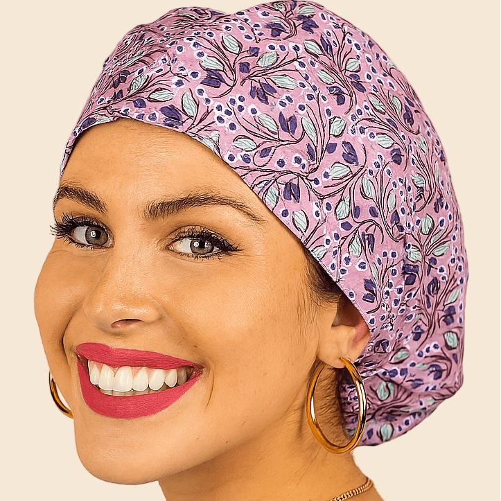 A woman with a purple and blue patterned hair cap and large hoop earrings is smiling at the camera.