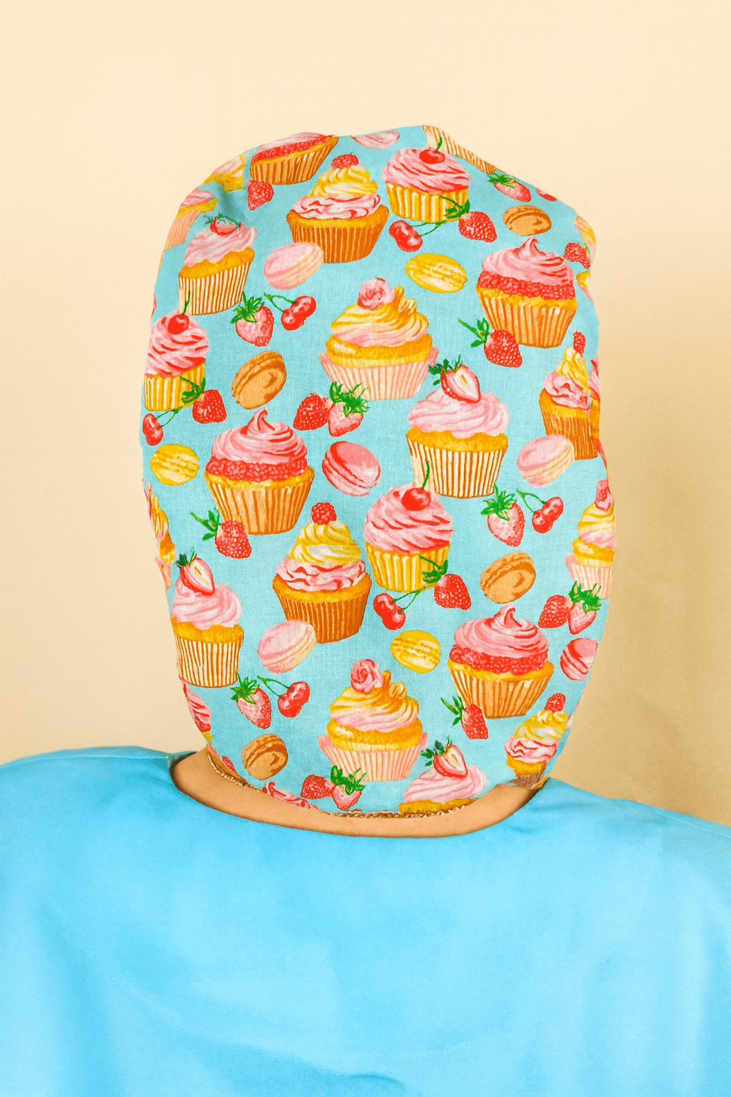 a person wearing a blue shirt with a pattern of cupcakes and strawberries printed on it.