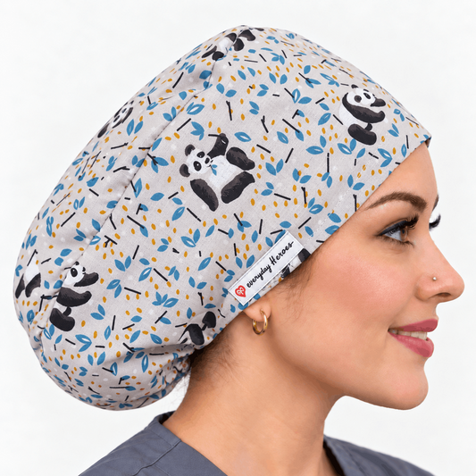 A woman in profile wearing a light gray scrub cap with a panda and leaf print. 