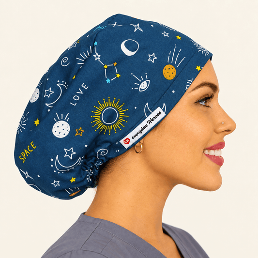 A woman in profile wearing a navy blue scrub cap with a space-themed print of stars, moons, planets, and constellations, along with the words 'SPACE' and 'LOVE'. 