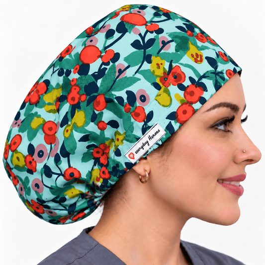A woman in profile wearing a teal scrub cap with a colorful floral pattern. The fabric cap features red, yellow, and pink flowers with green leaves on a light teal background.
