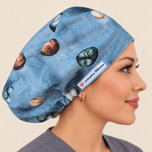 A woman in profile wearing a blue scrub cap with a polished stone pattern, shown against a plain BLUE background. 