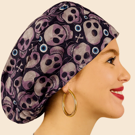 A woman wearing a blue top and a large skull-patterned hat is smiling.