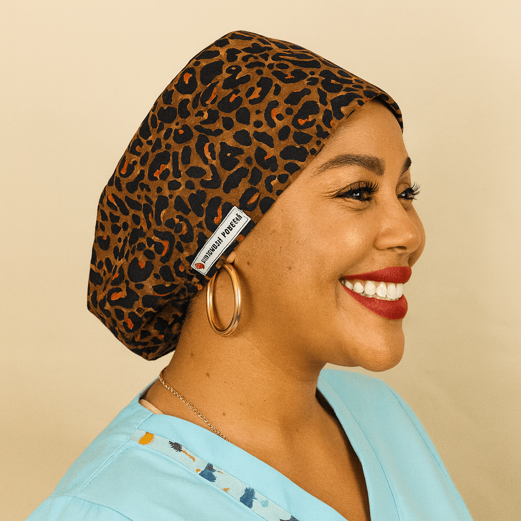 Smiling woman wearing a leopard print satin euro scrub cap with name embroidery tag. Perfect custom scrub cap for nurses, surgeons, and medical staff. Stylish cheetah scrub hat combines comfort, elegance, and function — ideal for surgery, clinic, or veterinary use. Premium handmade medical headwear with satin lining for hair protection and professional look.