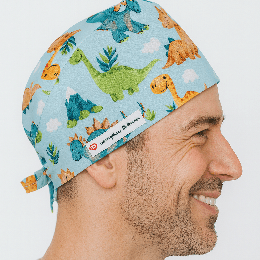 Smiling male doctor wearing a light blue scrub cap with colorful dinosaur prints. Comfortable and adjustable men’s surgeon hat designed for doctors, surgeons, and pediatric professionals. A fun and practical gift for doctors who bring joy to their patients.