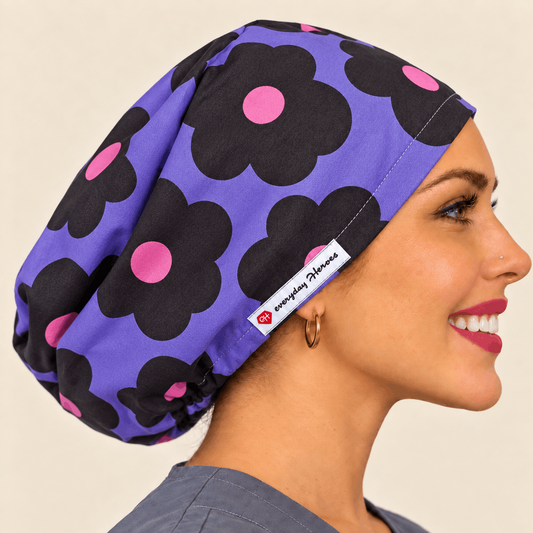 A woman in profile wearing a purple scrub cap with a black and pink floral pattern. 