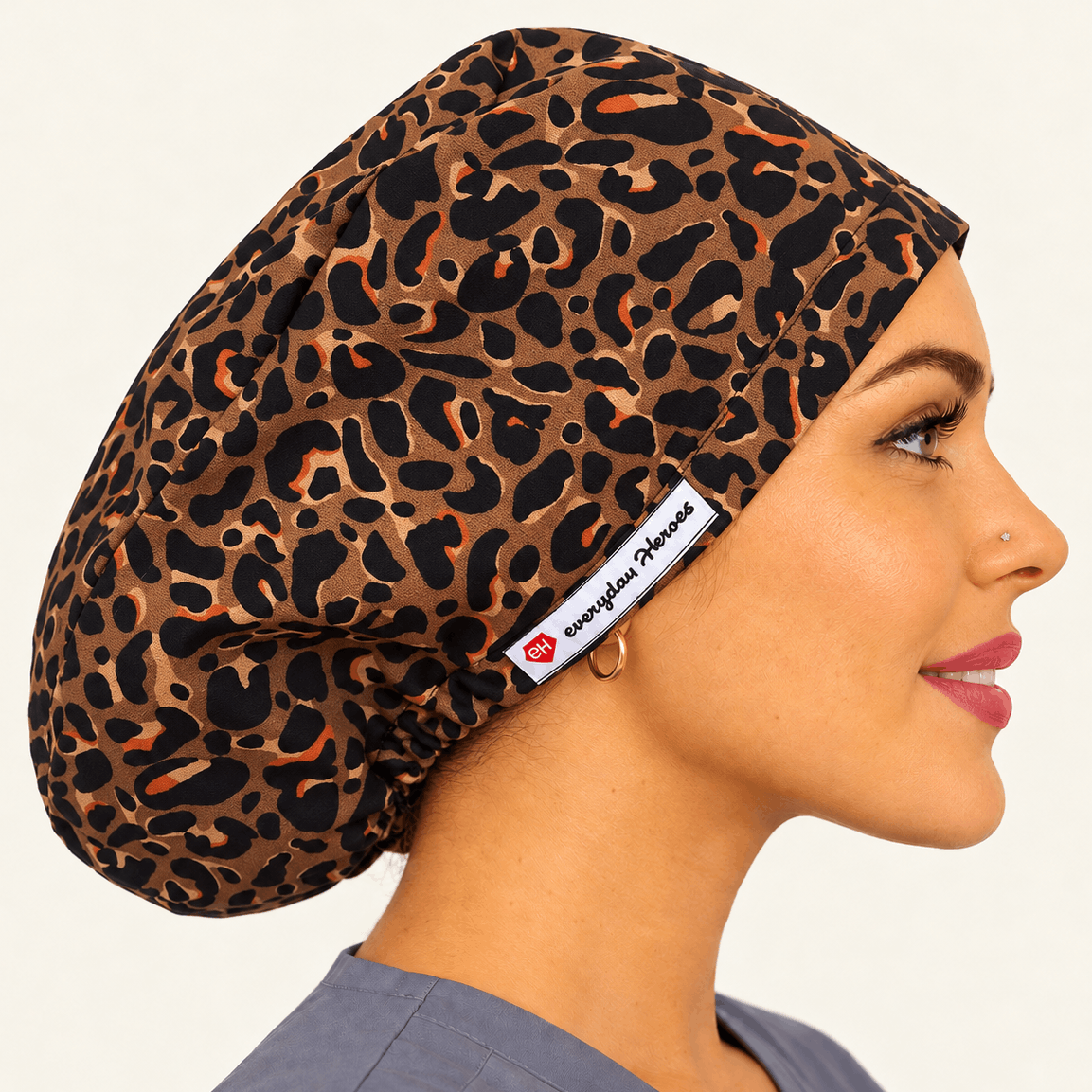 A woman in profile wearing a leopard-print scrub cap. The cap features a brown, black, and tan animal print pattern 