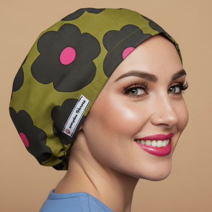 Scrub cap floral with smiling healthcare professional - olive green bouffant euro scrub hat featuring large black daisies with pink centers - satin lined surgical OR cap for midwife medical professionals - anatomy personalized with embroidery option - custom name embroidery available - gift idea for nurses doctors midwives - adjustable elastic fit - woman with hot pink lipstick green hazel eyes showing confident smile  Everyday Heroes brand - professional medical headwear retro mod daisy pattern