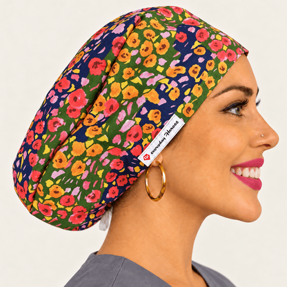 A woman in profile wearing a floral-patterned scrub cap. The cap features a vibrant multicolor floral print on a navy blue background with pink, yellow, orange, and green flowers.