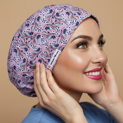 Purple goggi floral scrub cap profile view with woman looking up touching cap - mauve bouffant surgical hat featuring blue navy flowers mint turquoise leaves botanical pattern - euro style medical headwear with custom satin lining name embroidery - professional nurse scrub cap - Everyday Heroes
