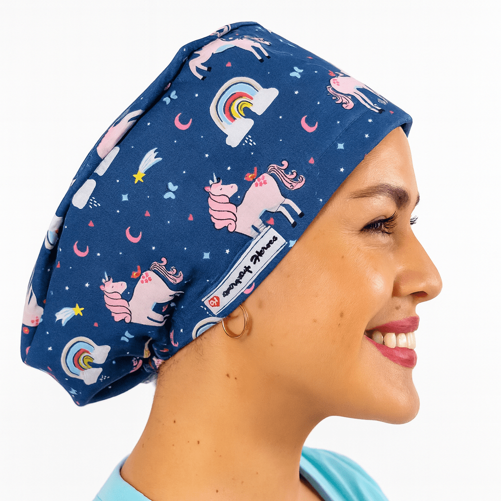 Smiling woman wearing a navy euro scrub cap with pink unicorns, rainbows, and stars print. Fun pediatric cartoon scrub hat, customizable with name embroidery. Ideal for nurses, surgeons, and pediatric staff working in the operating room.