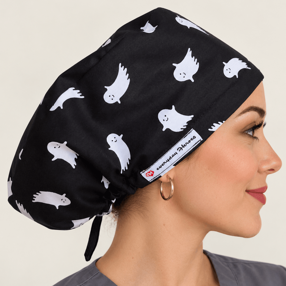 A woman in profile wearing a black scrub cap with a white ghost pattern. 